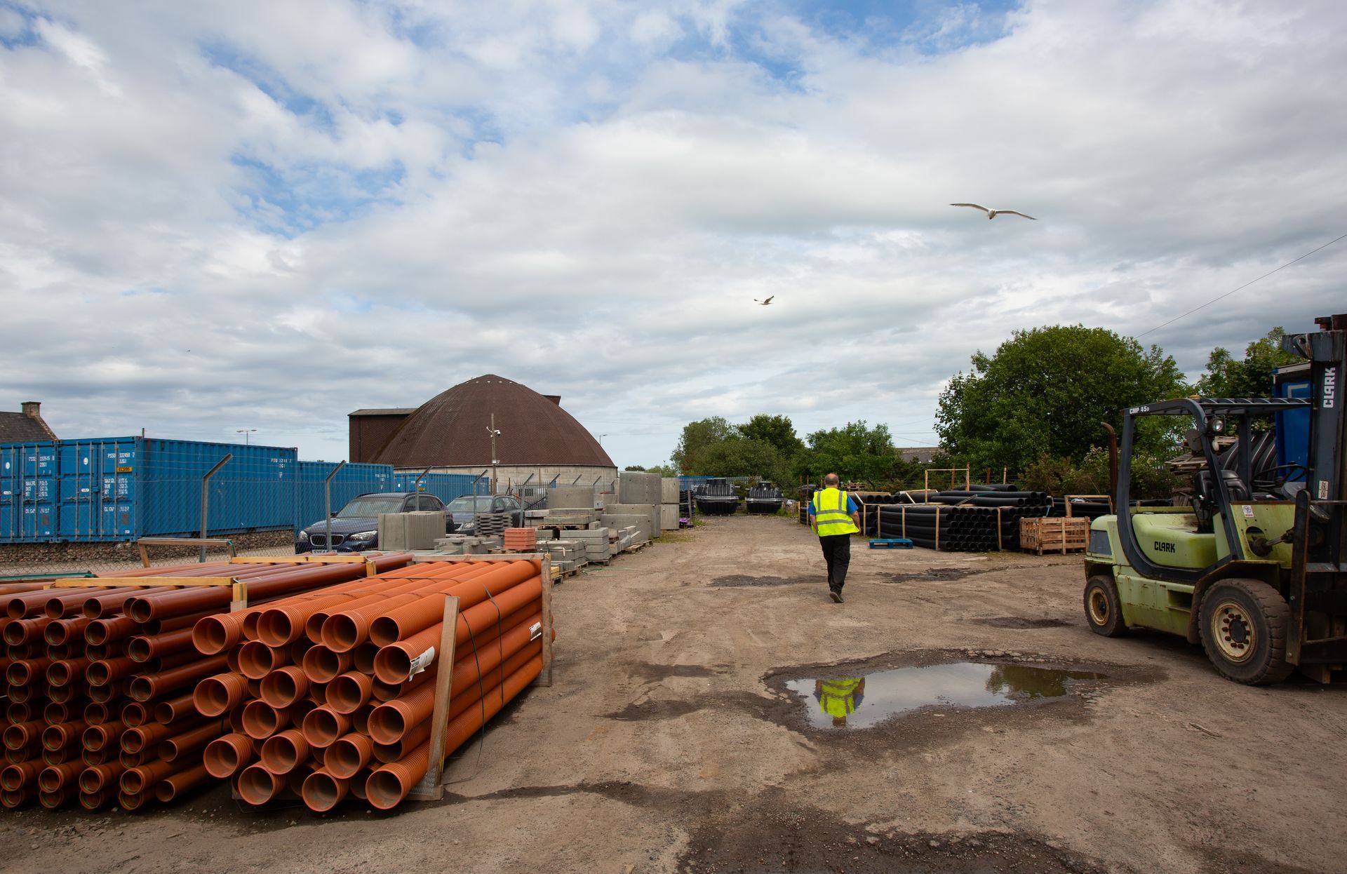 A man in a yellow vest is walking through a construction site.