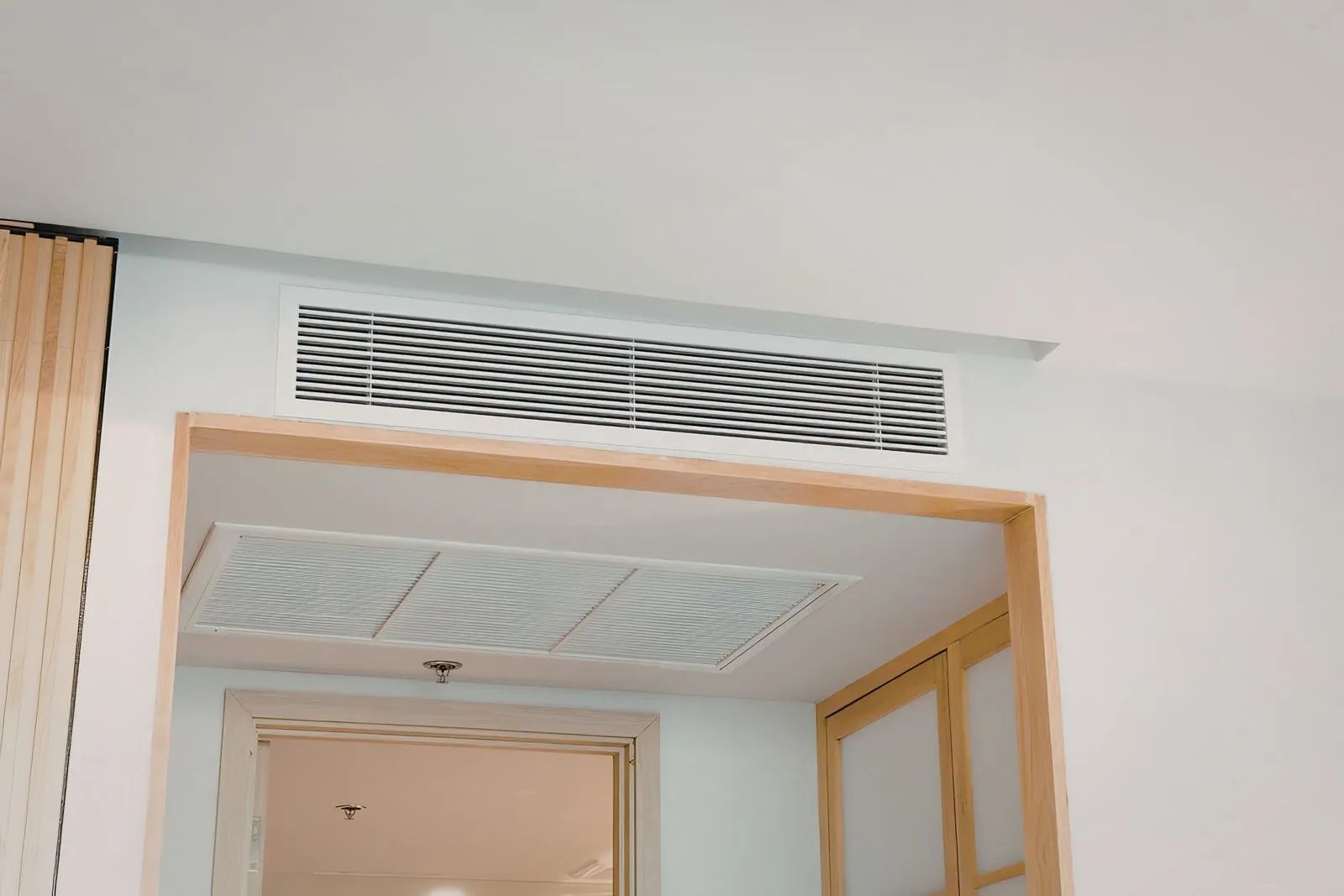Open doorway beneath a decorative air vent in a light-colored hallway.