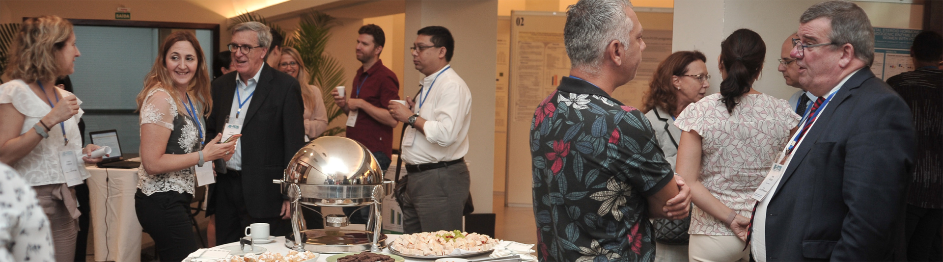Guests chatting around a buffet table with a silver serving dish at a formal indoor event