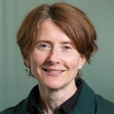 Portrait of a smiling person with short brown hair against a muted green background