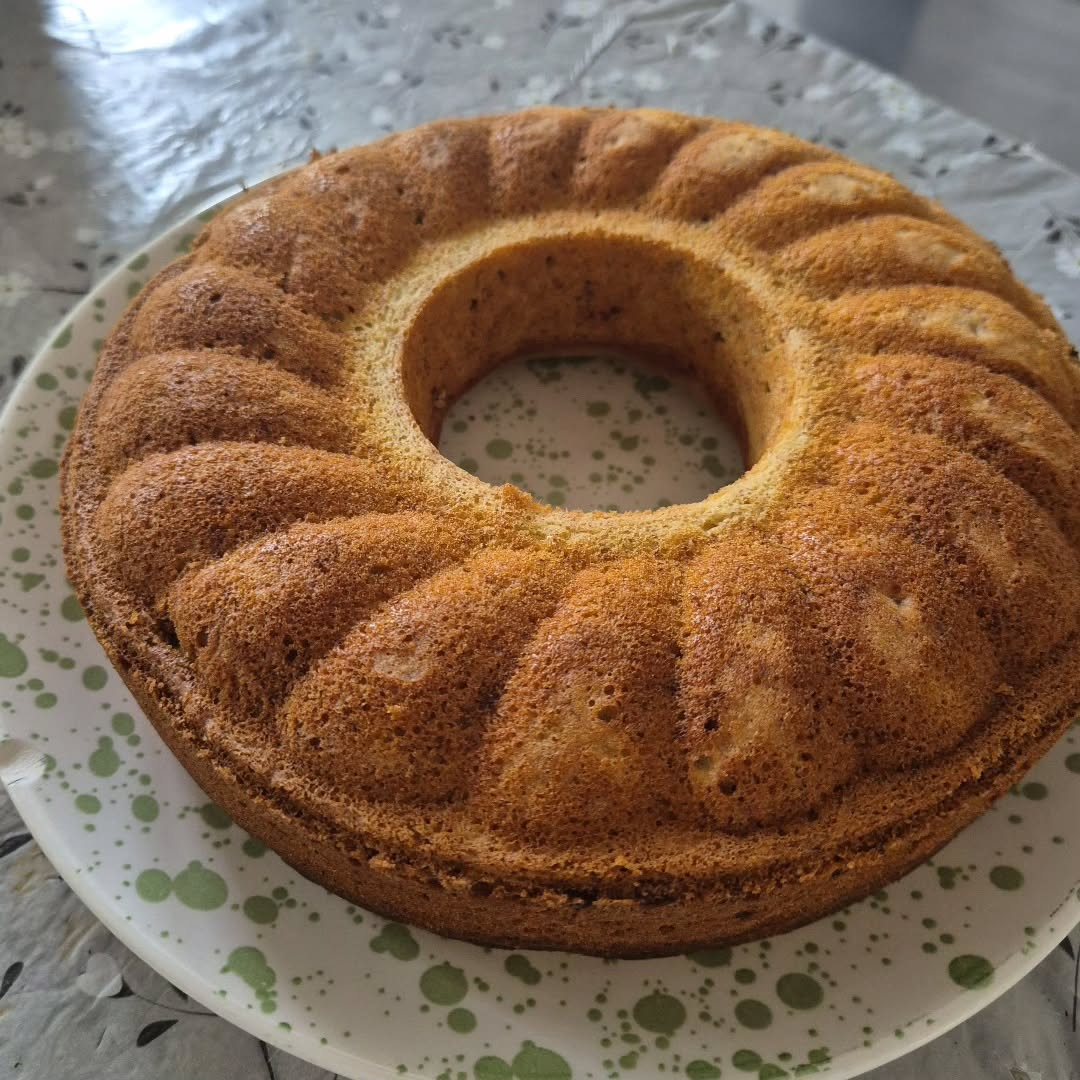 Ciambella su un piatto verde e bianco; la crosta è dorata.