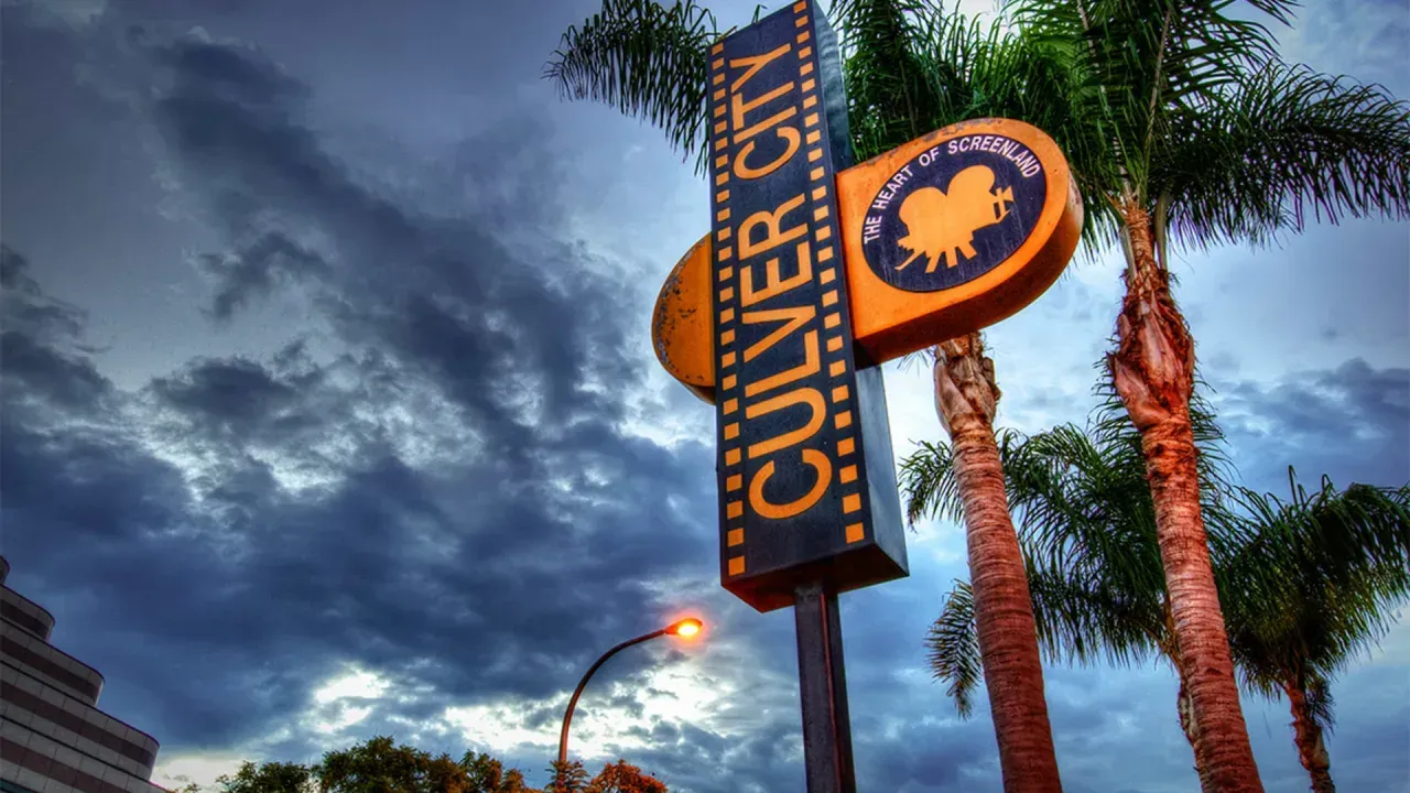 Culver City community sign with dark clouded sky and palm trees, buy a home in Culver City with the top realtors