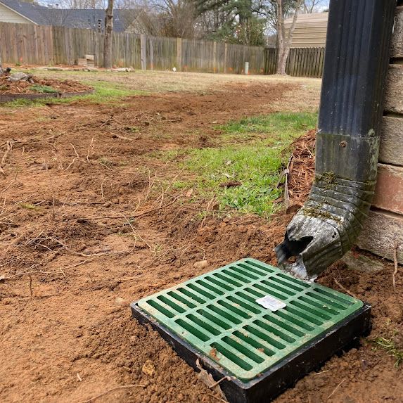 irrigation solution shows a green drain cover is sitting next to a drain pipe in a yard.