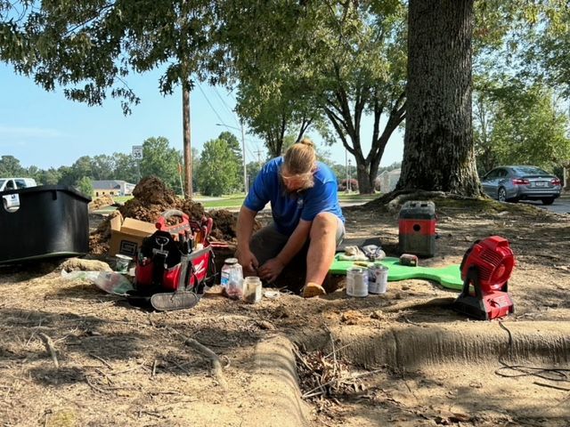 one of SouthernGrounds men kneeling down in the dirt for a new irrigation solution services.