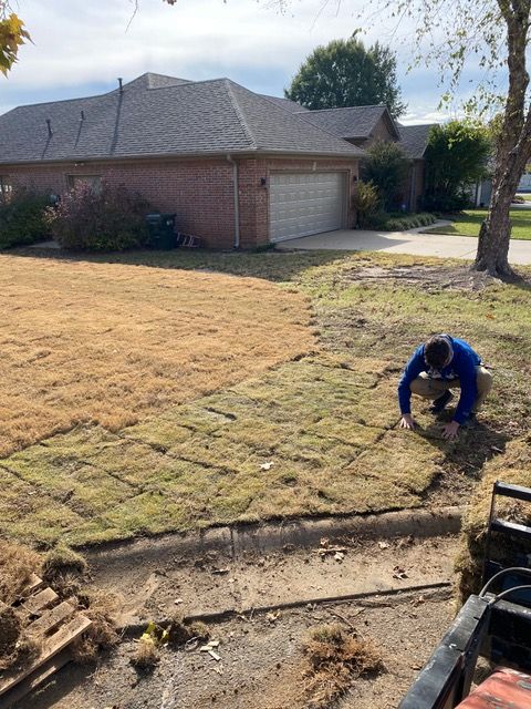 a man is working on a lawn in front of a house .