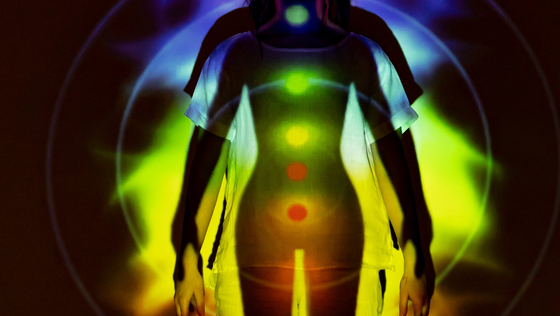 A silhouette of a woman with a rainbow of chakras on her body.