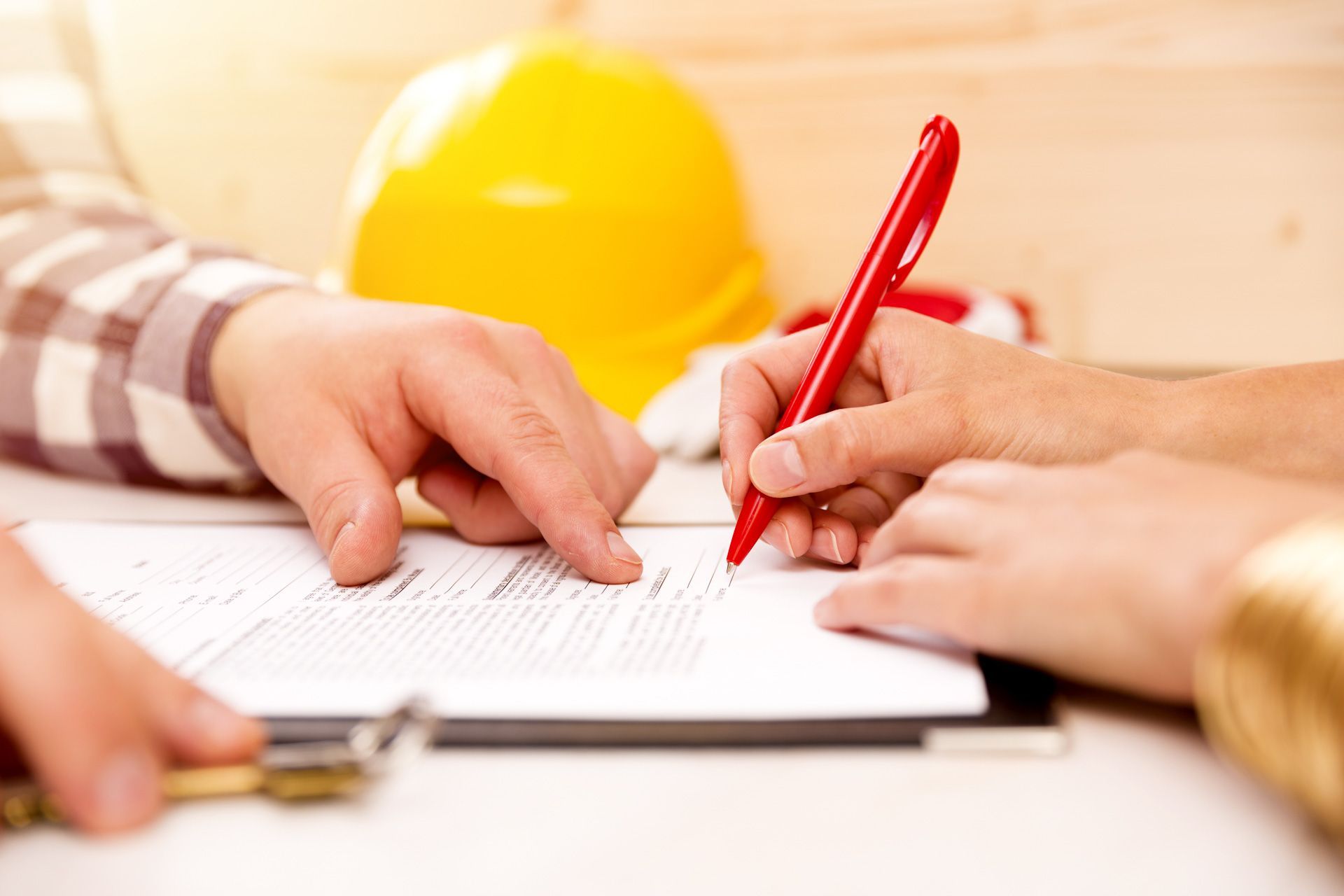 A couple of people are signing a contract on a clipboard.