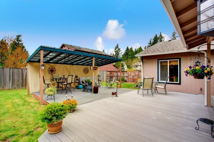 Backyard patio with pergola, potted plants, outdoor seating, and a small shed beside a lawn