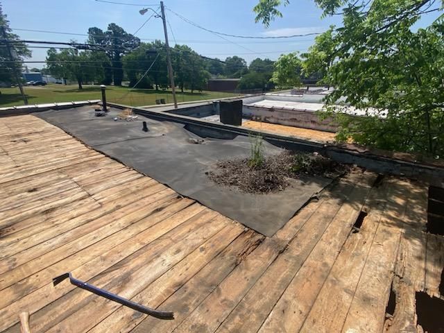 A wooden deck with a black tarp on top of it.