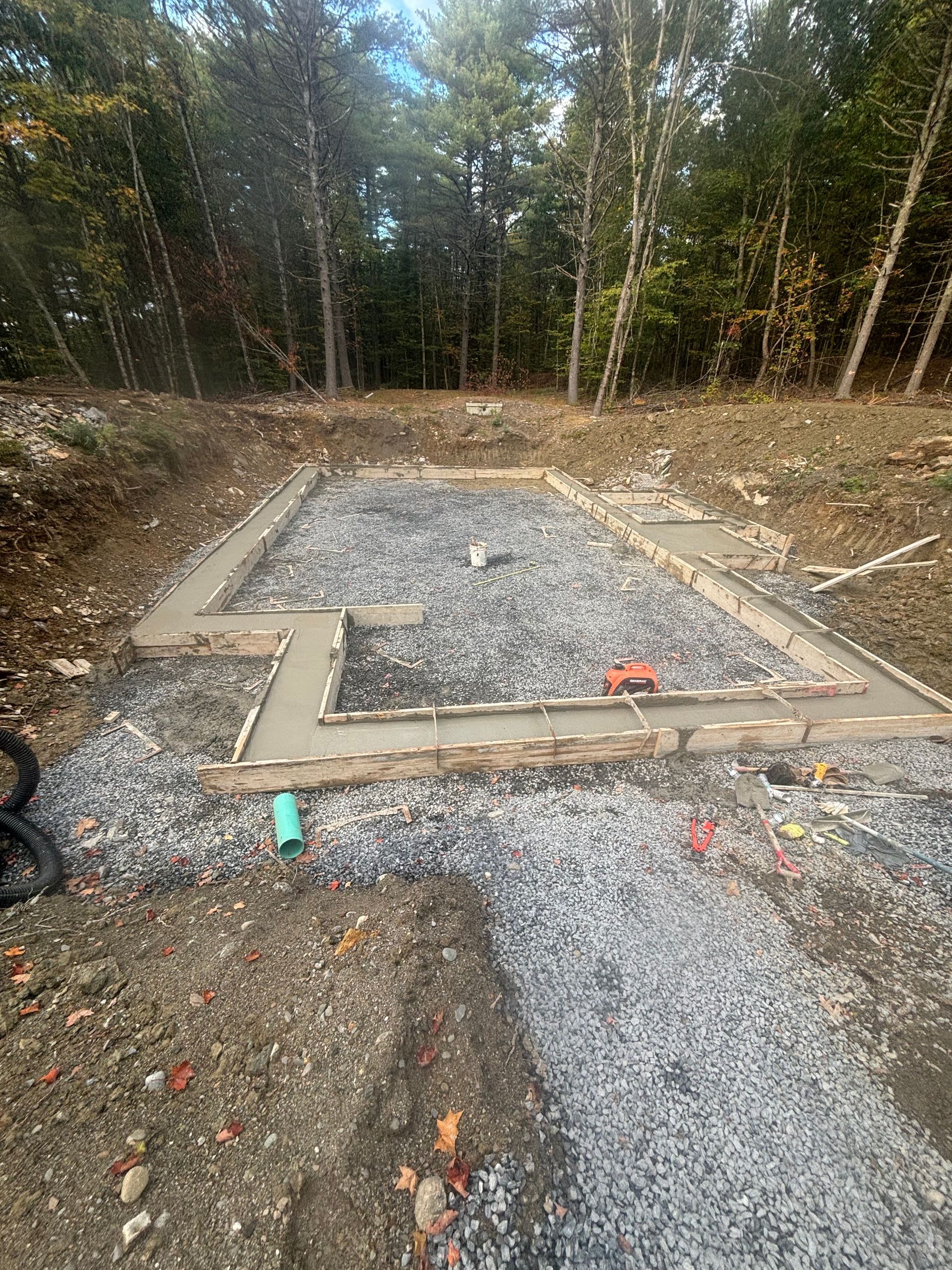 A concrete foundation is being built in the middle of a dirt field.