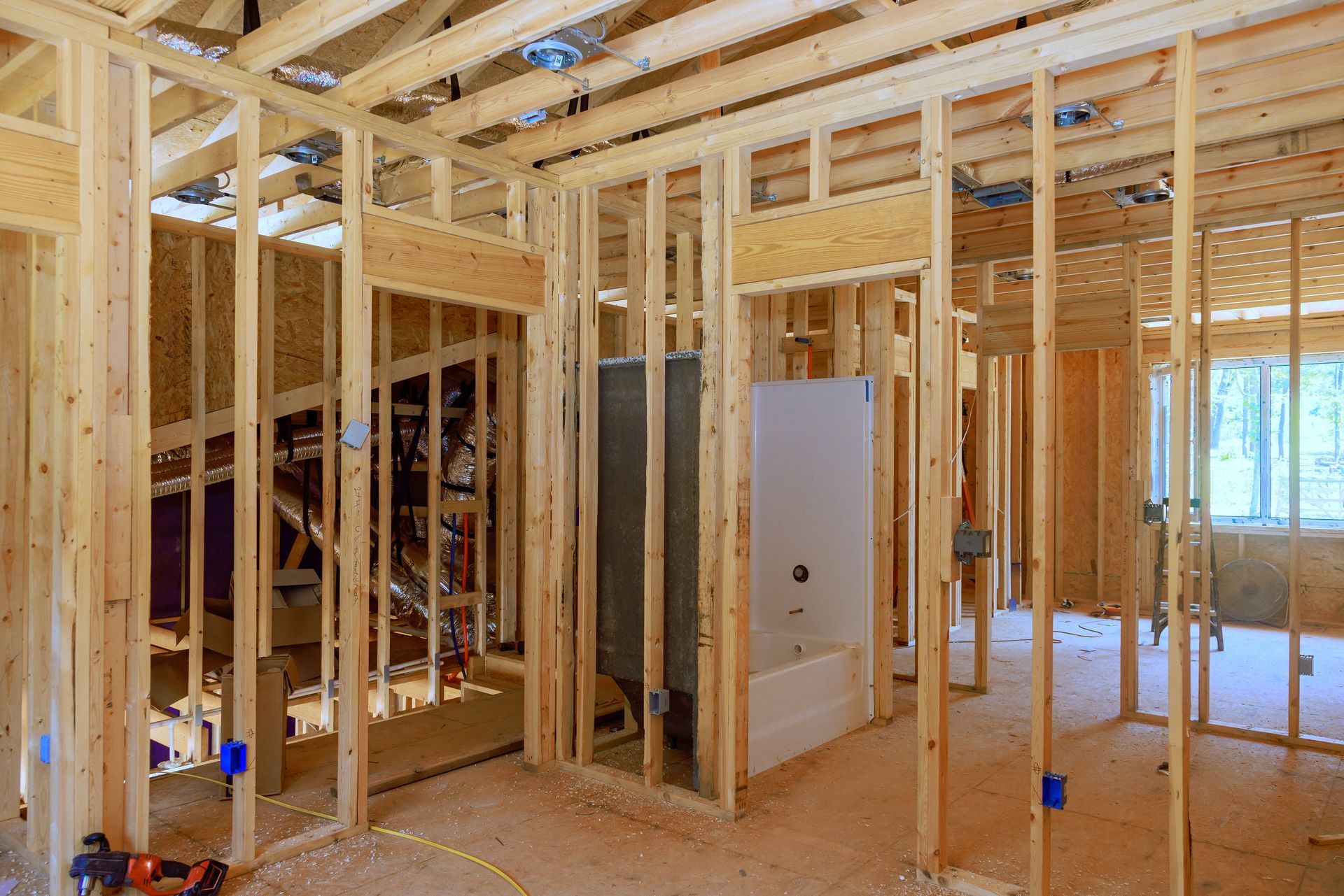 Wood-framed house interior under construction with exposed studs and bright windows
