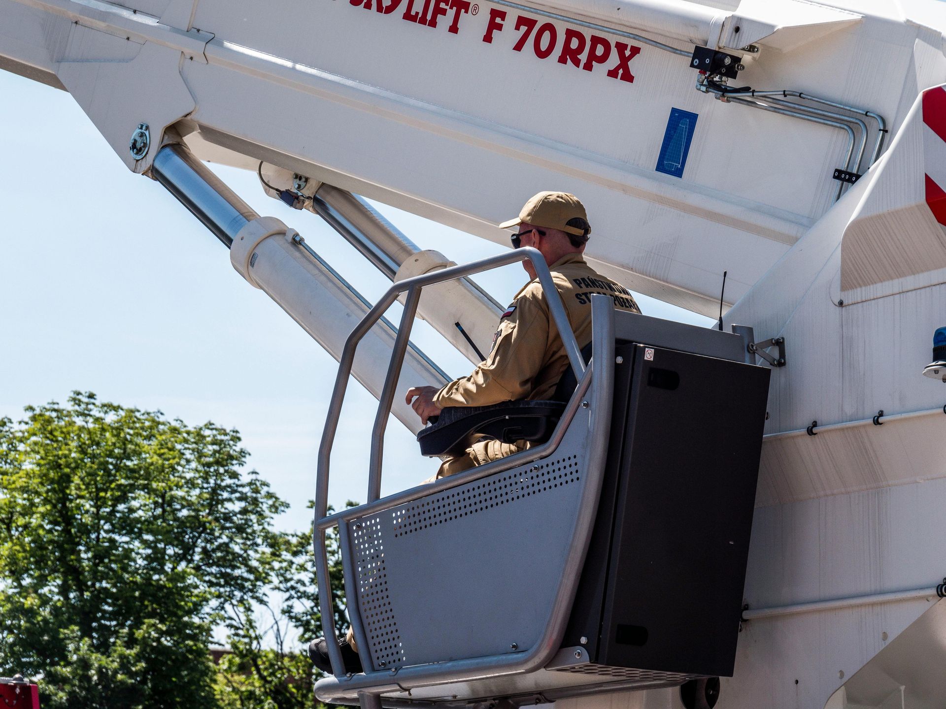 Person operating an aerial lift. The person is seated inside the lift's control cabin.