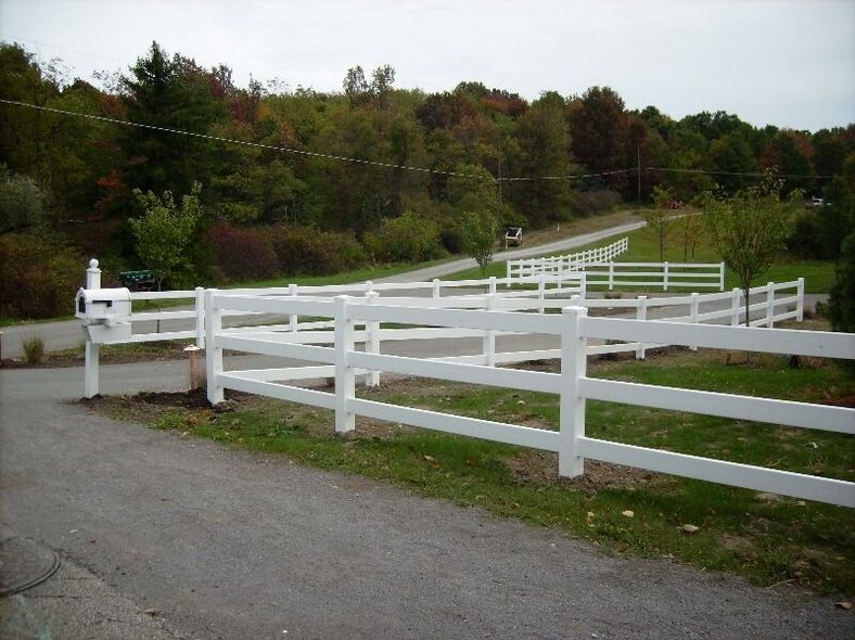 White wooden fence along a gravel road in a rural green landscape