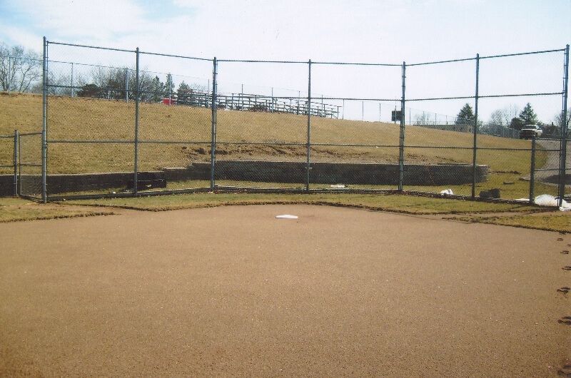 Empty baseball field with dirt infield and chain-link backstop under a clear sky