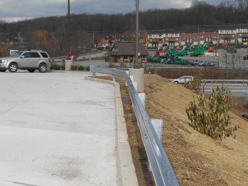 Parking lot beside a road with a metal guardrail and snowy ground under an overcast sky