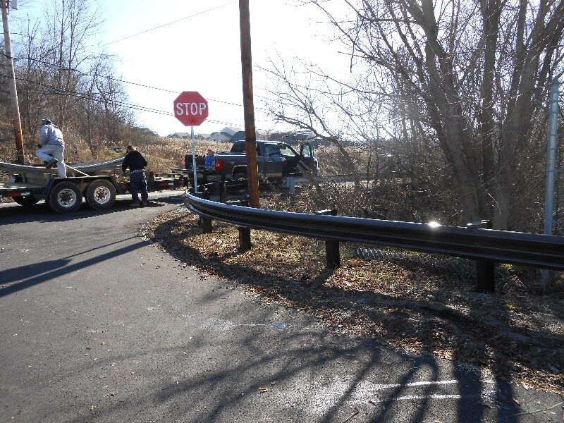 Roadside accident scene with a damaged car, tow truck, and stop sign on a winter street