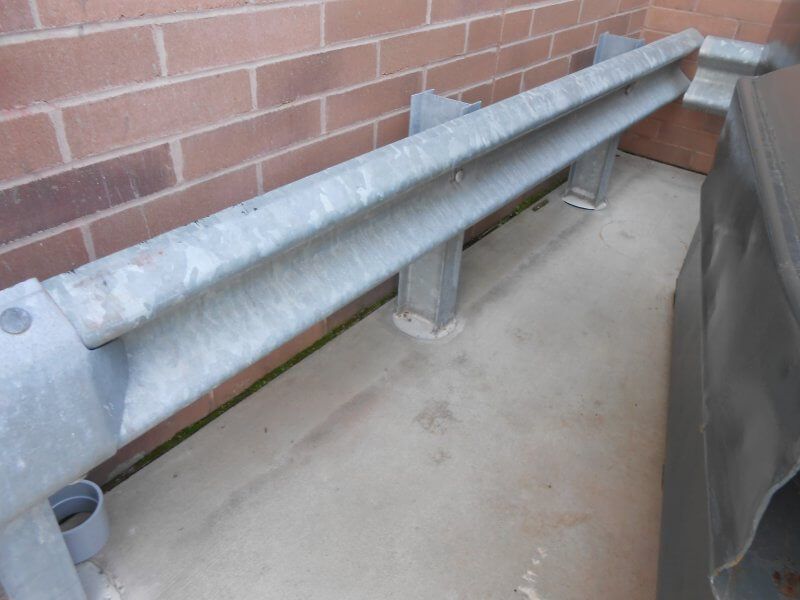 Metal guardrail beside a brick wall on a concrete walkway