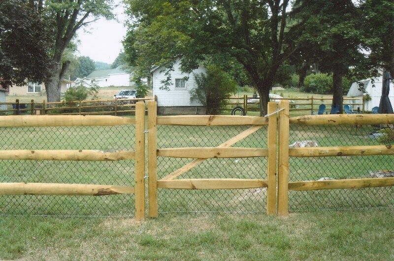 Wooden fence with crossbuck gate in a grassy park under trees