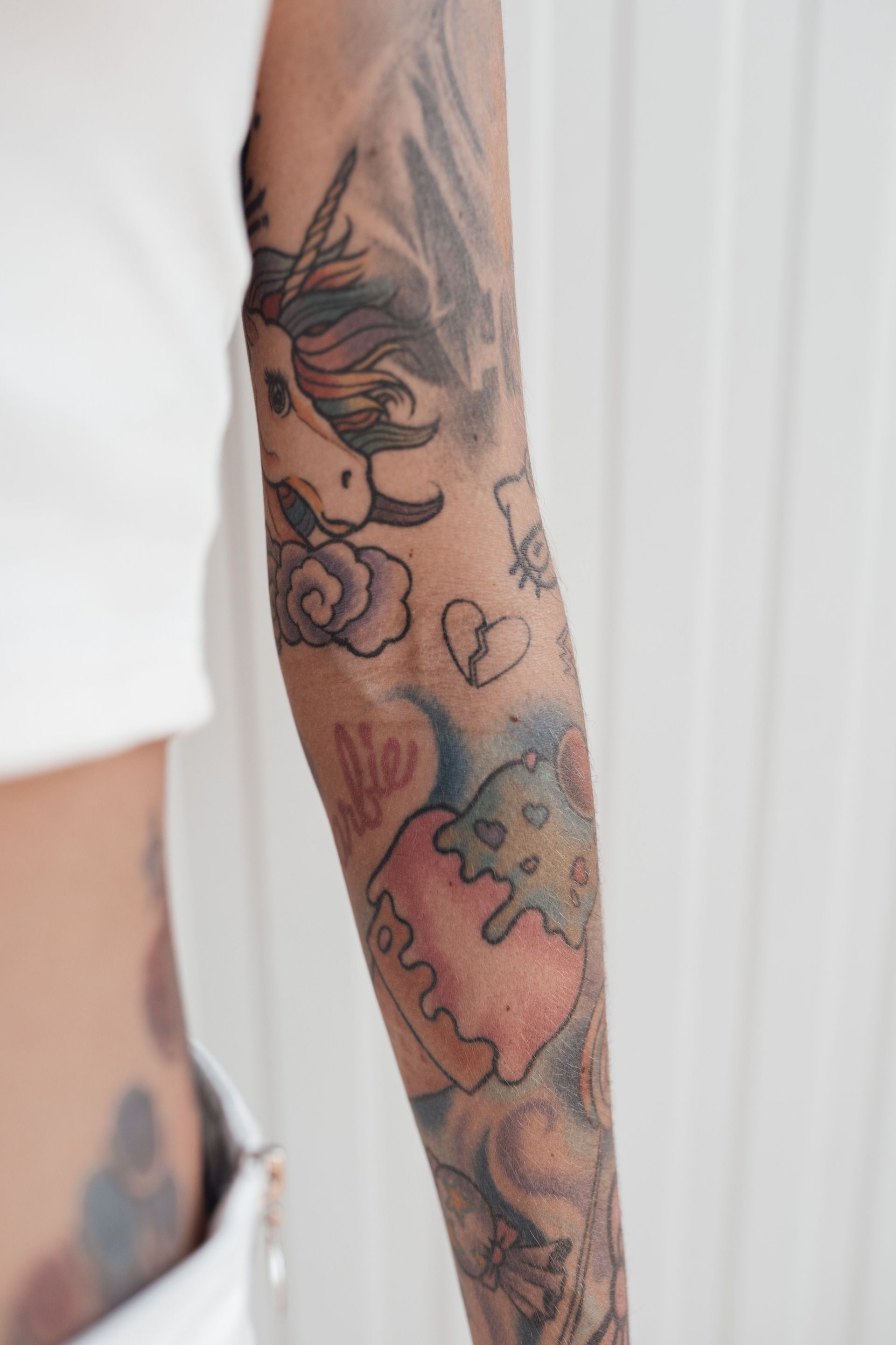 Close-up of a tattooed arm with colorful floral and abstract designs