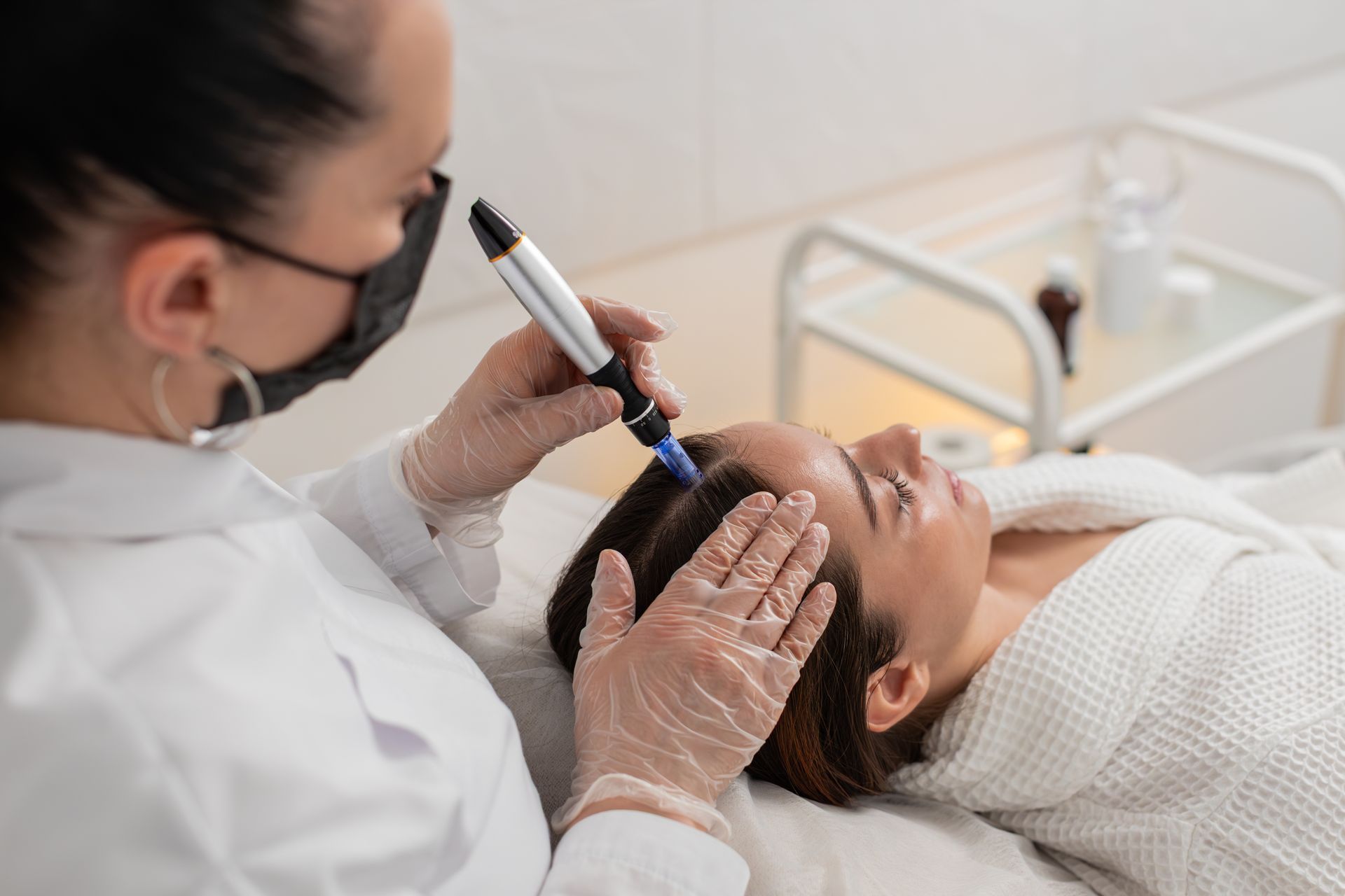 A professional uses a medical device on a person’s forehead in a clinic setting.