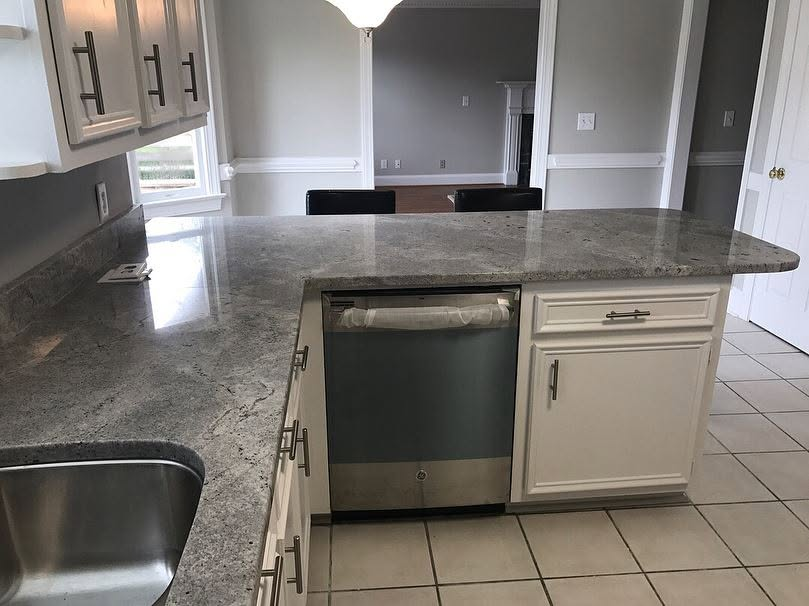 Kitchen with granite countertops, sink, white cabinets, and a dishwasher under the island counter.