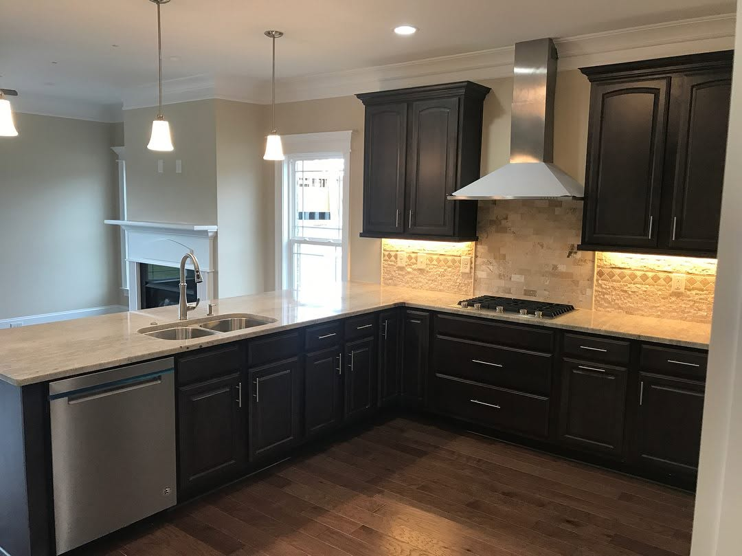 Modern kitchen with dark cabinets, light countertops, stainless appliances, and pendant lighting
