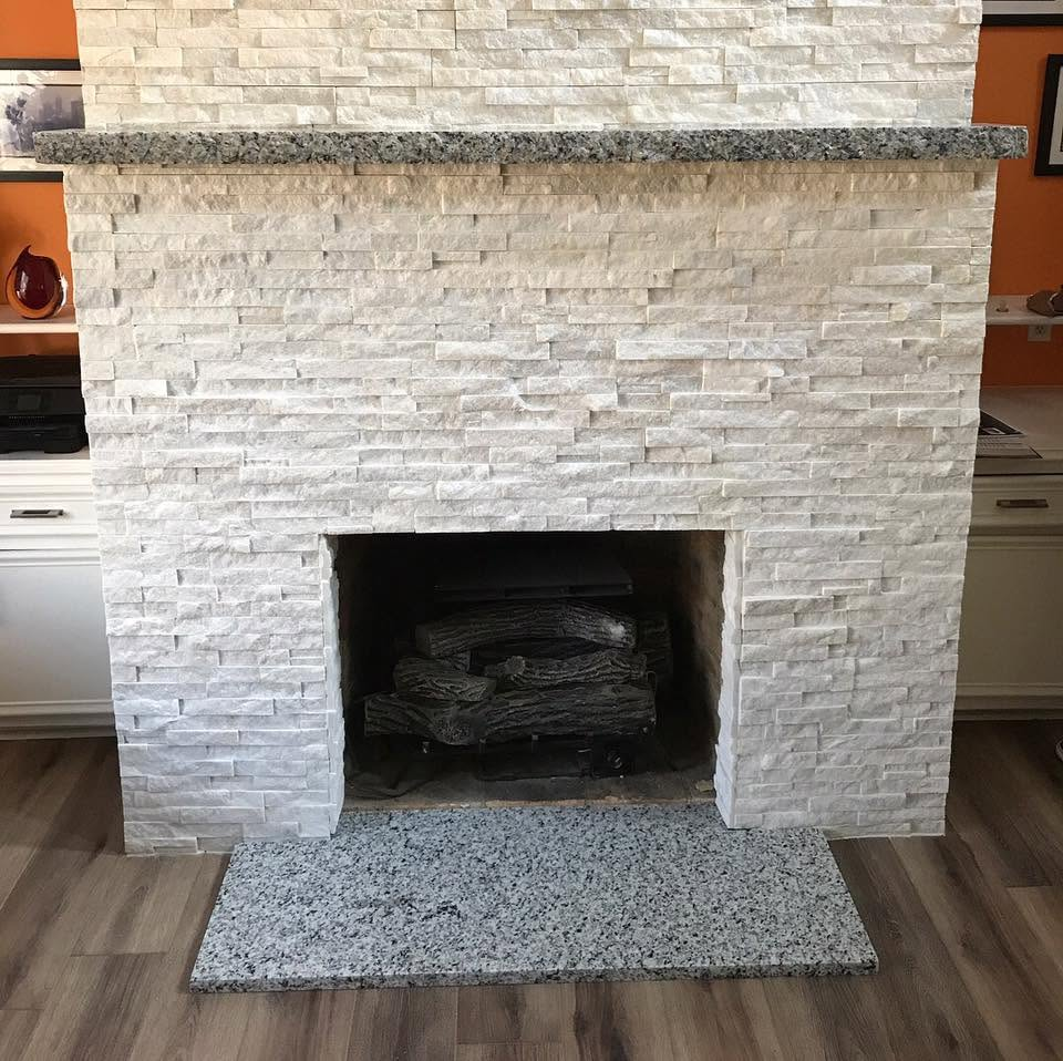 White stone fireplace with a gray hearth rug in a living room