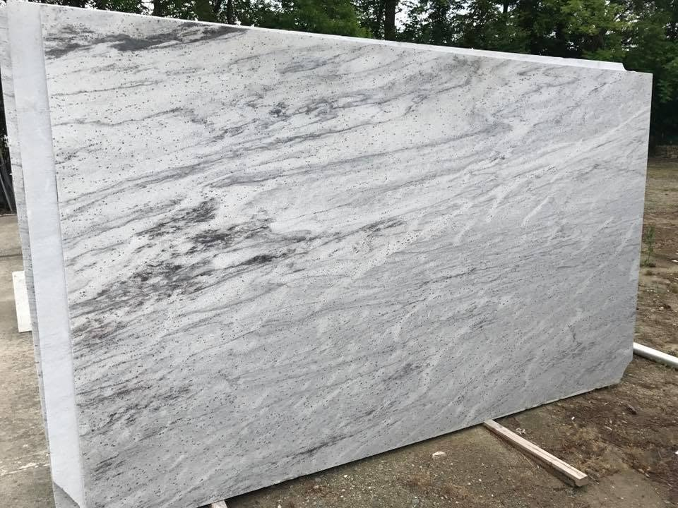 Large white-and-gray marble slab standing outdoors on supports