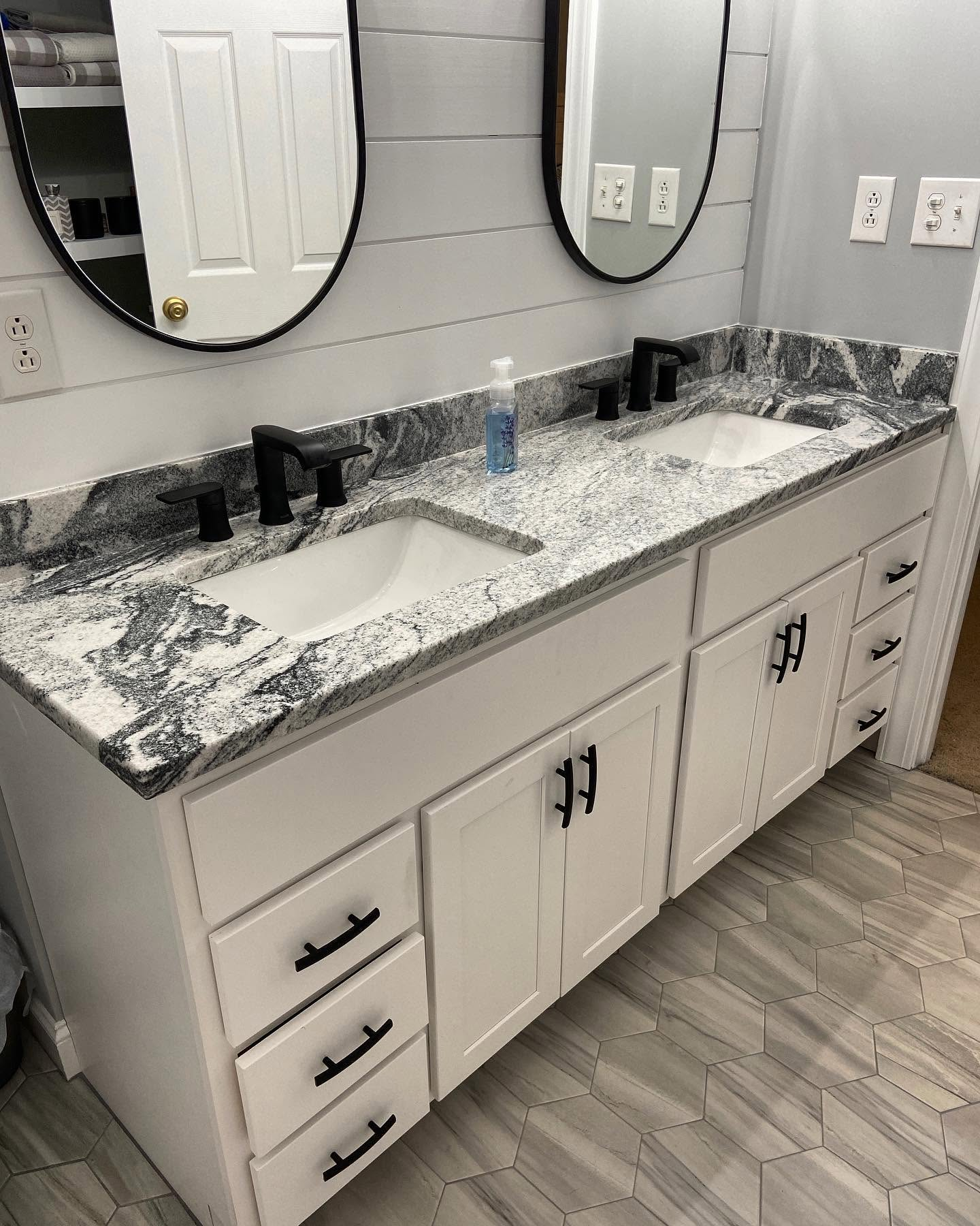 Modern bathroom vanity with black-and-white countertop, double sinks, and round mirrors