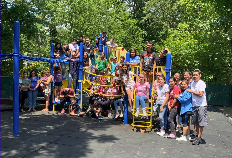A group of people are posing for a picture in front of a playground.