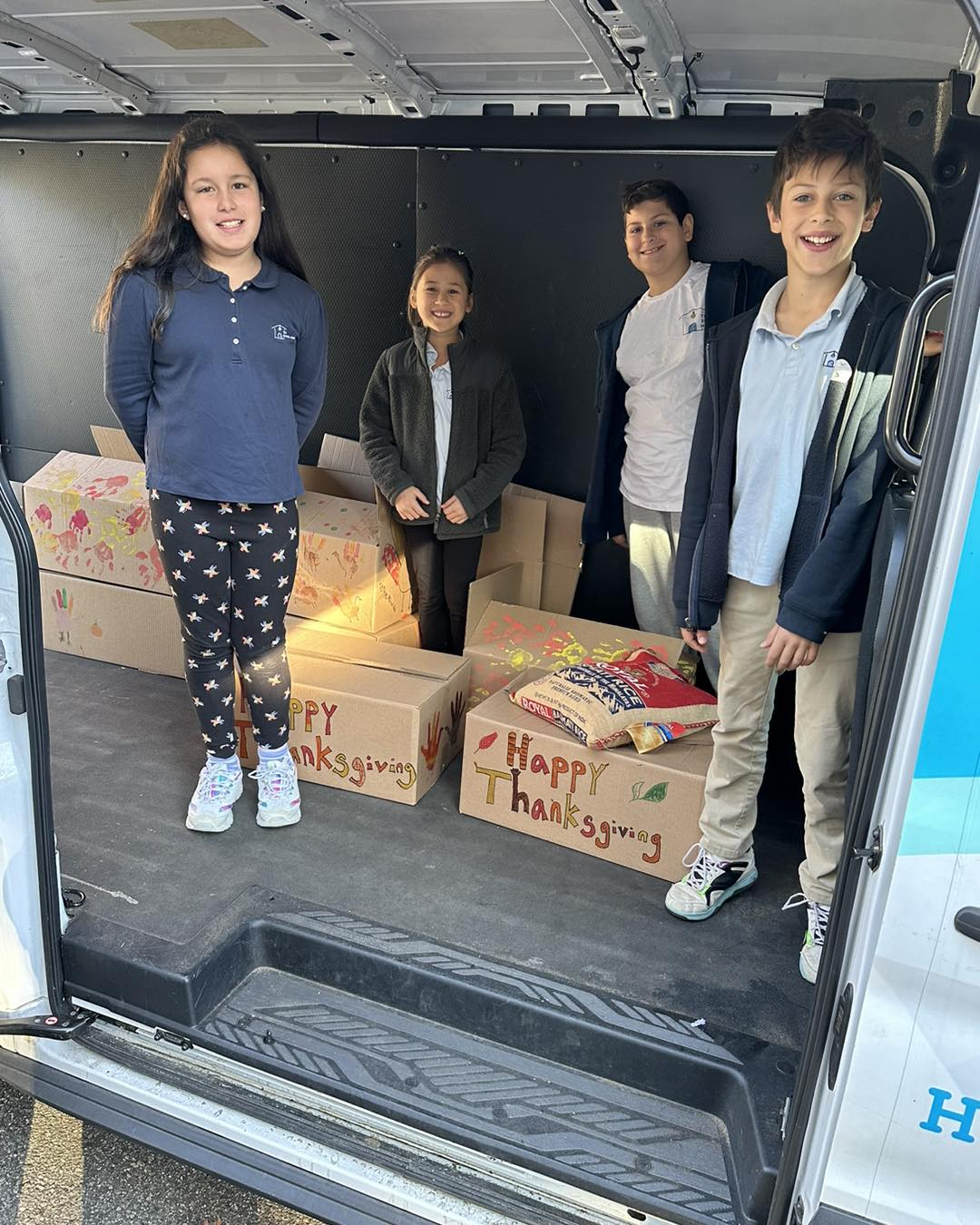 A group of children are standing in the back of a van.