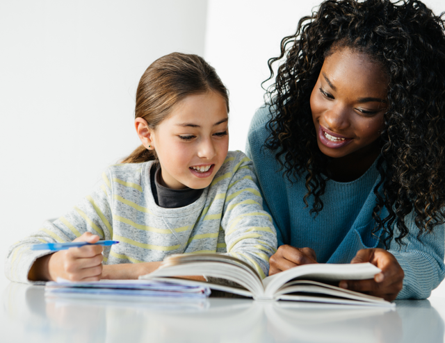 A girl and a female tutor reviewing work together.