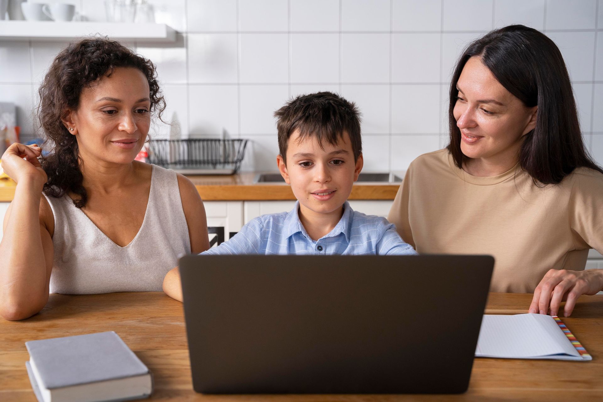 A family is sitting at a table looking at a laptop computer.