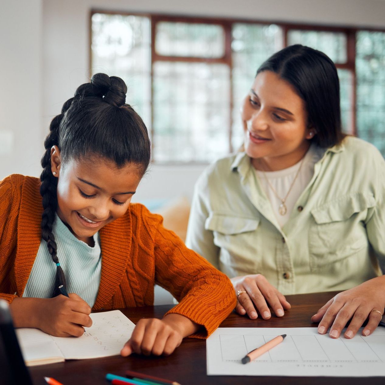 Two girls are sitting at a table looking at a book