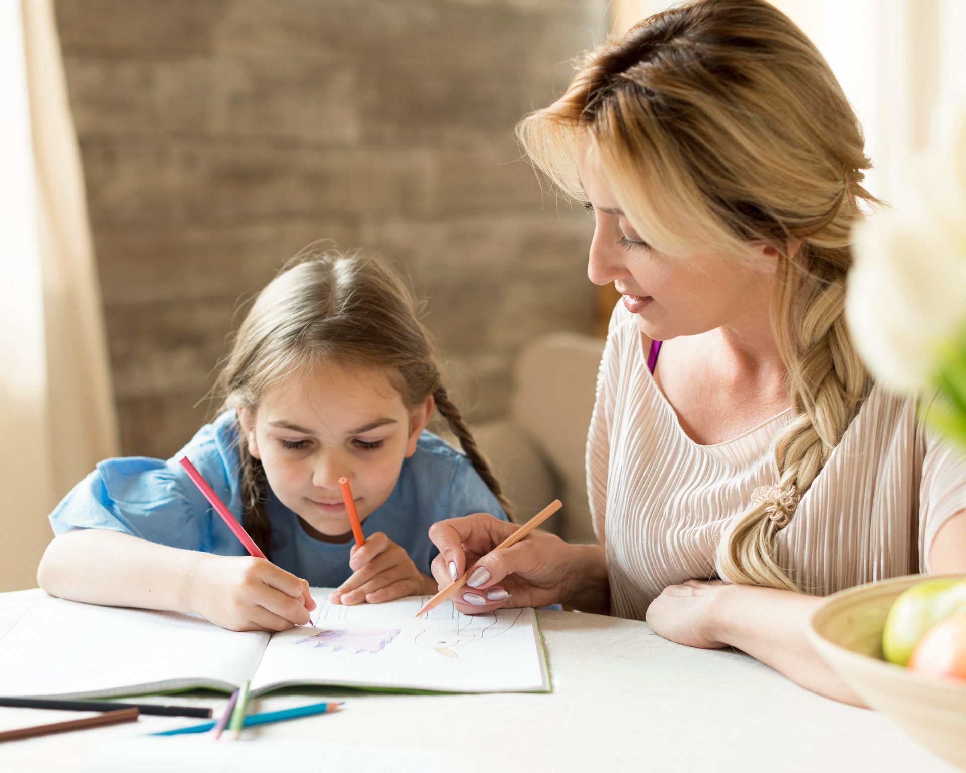 A woman is helping a little girl with her homework.