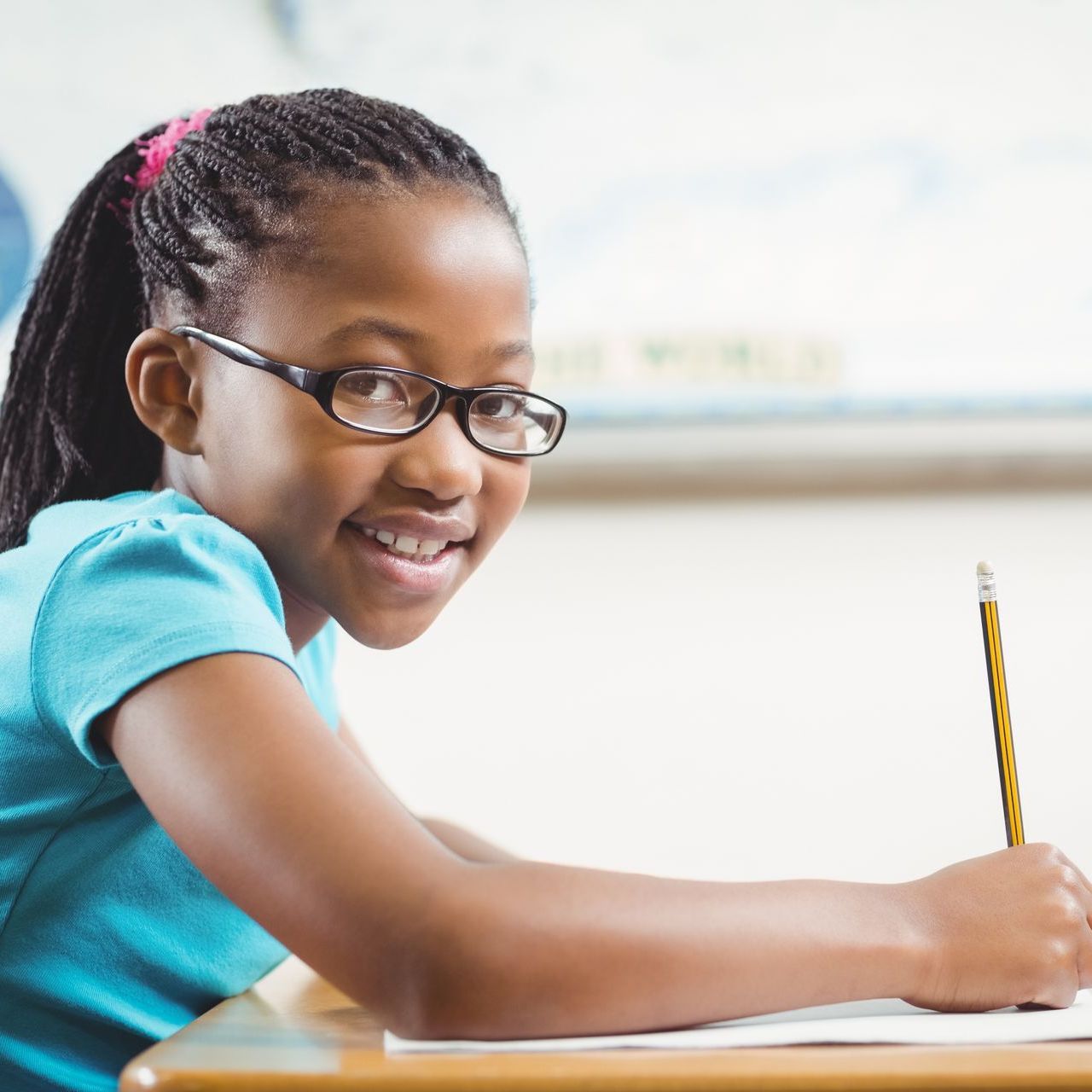 A young girl wearing glasses is writing on a piece of paper