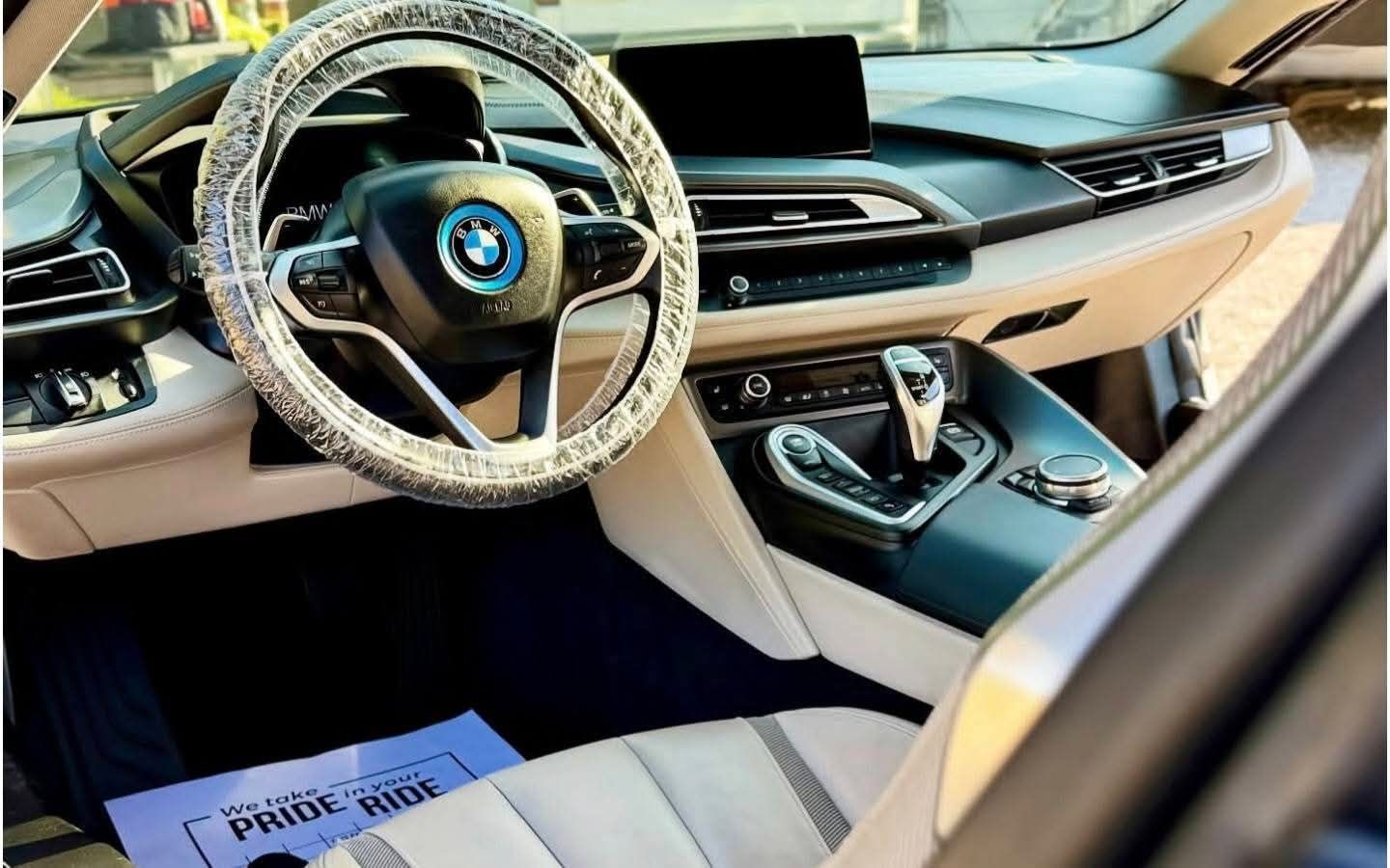 BMW car interior with beige and black dashboard, steering wheel, center console, and newspaper on the floor