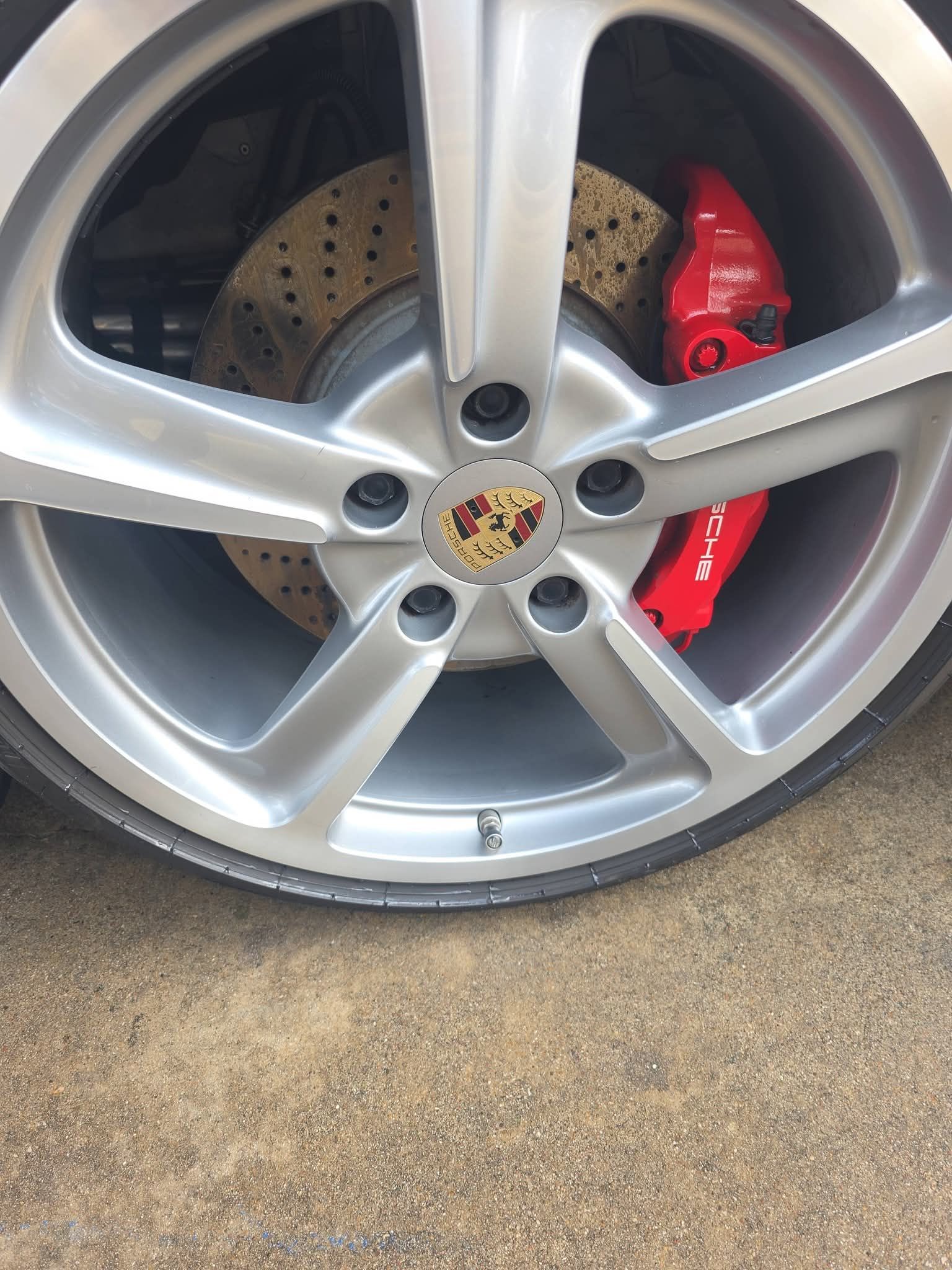 Close-up of a silver Porsche wheel with red brake caliper and drilled brake disc