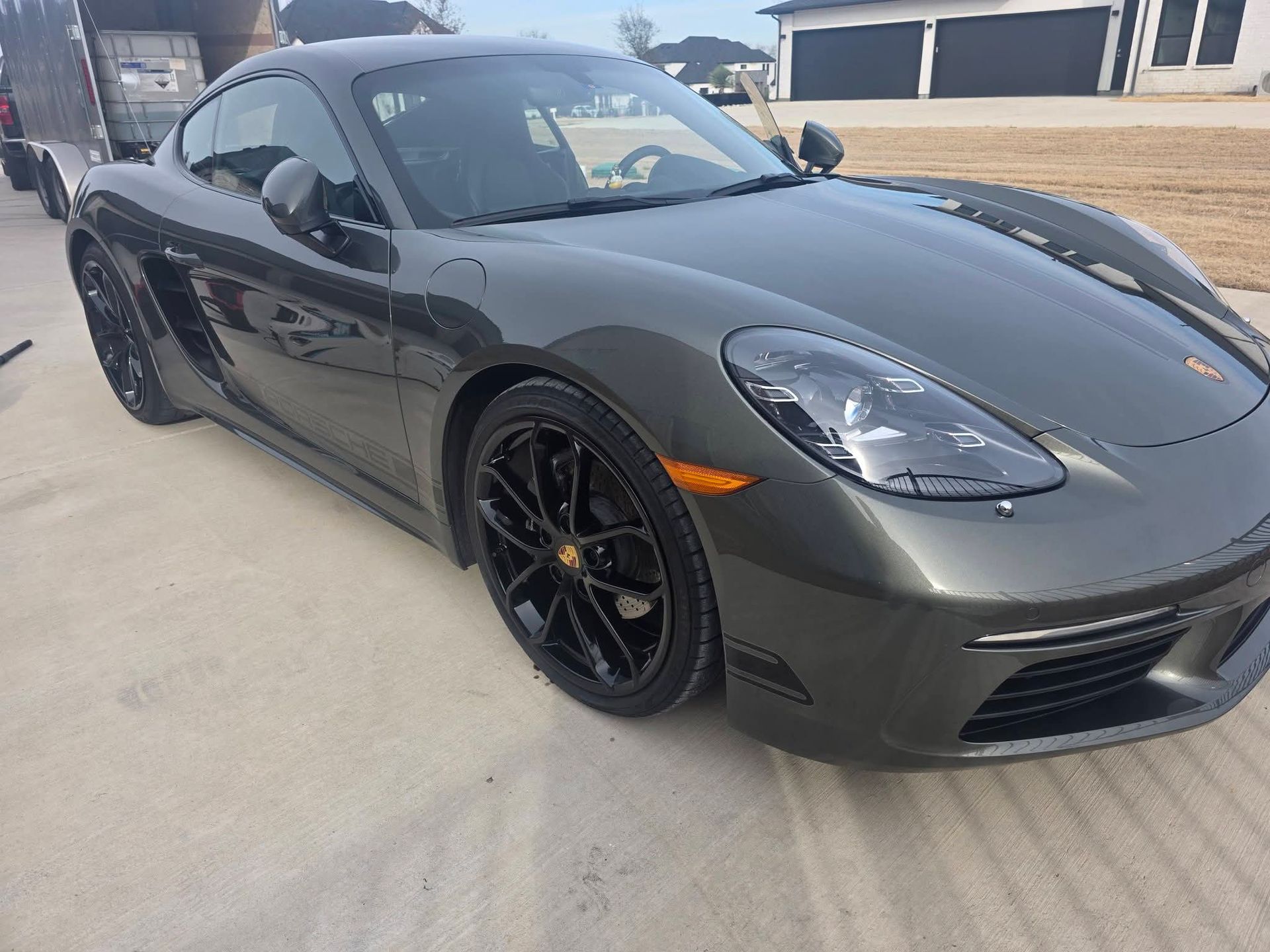 Gray sports coupe parked outdoors on a lot, front-left view, with black rims and a low-profile design
