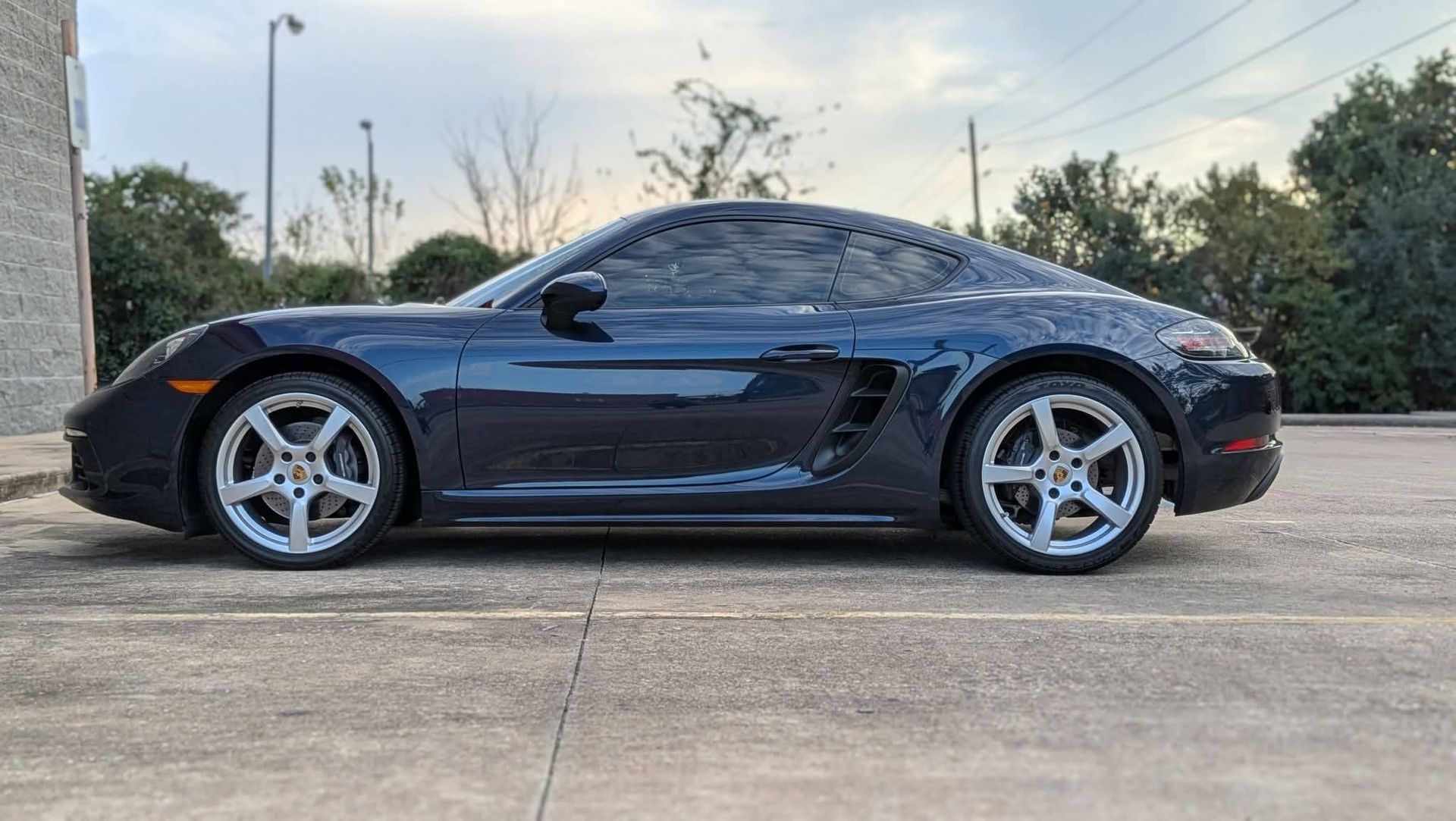 Black sports car parked on a concrete lot at sunset