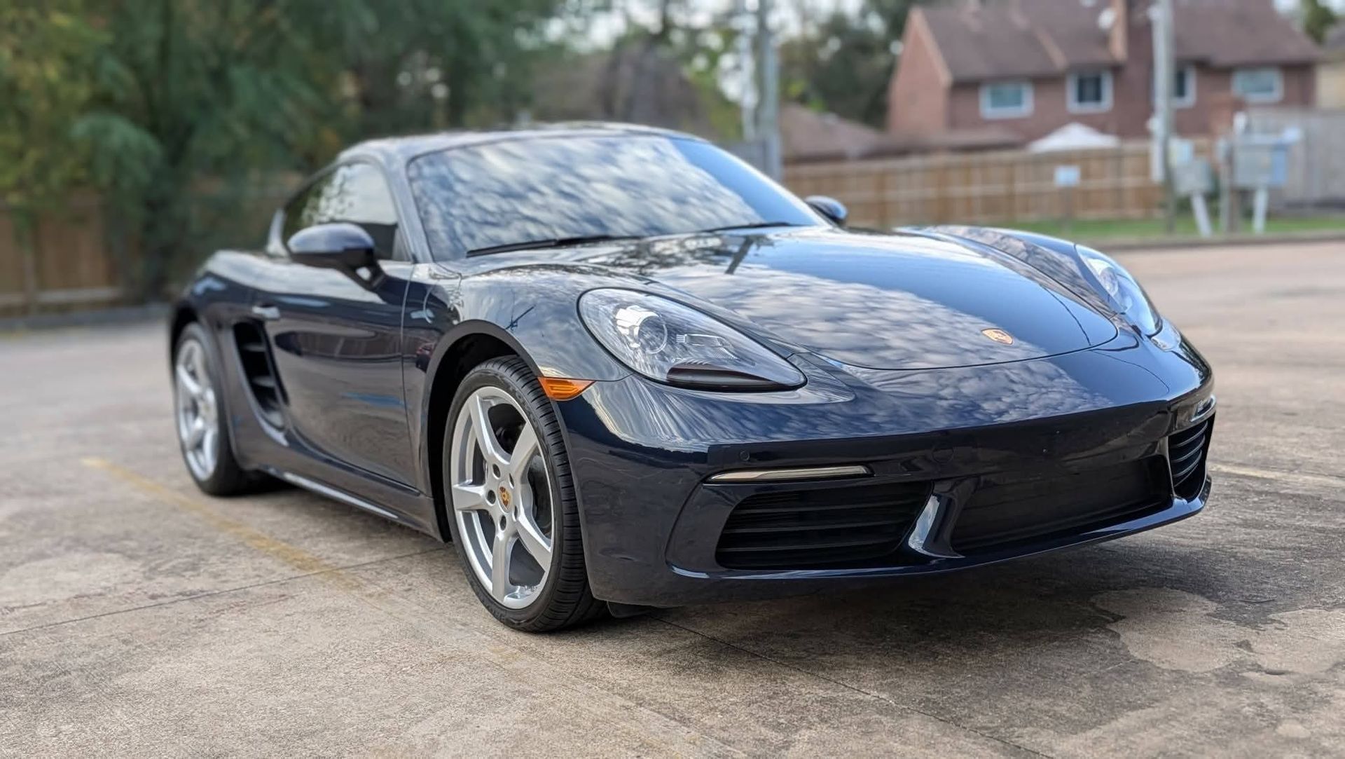 Hands polishing a glossy blue car headlight with a microfiber cloth