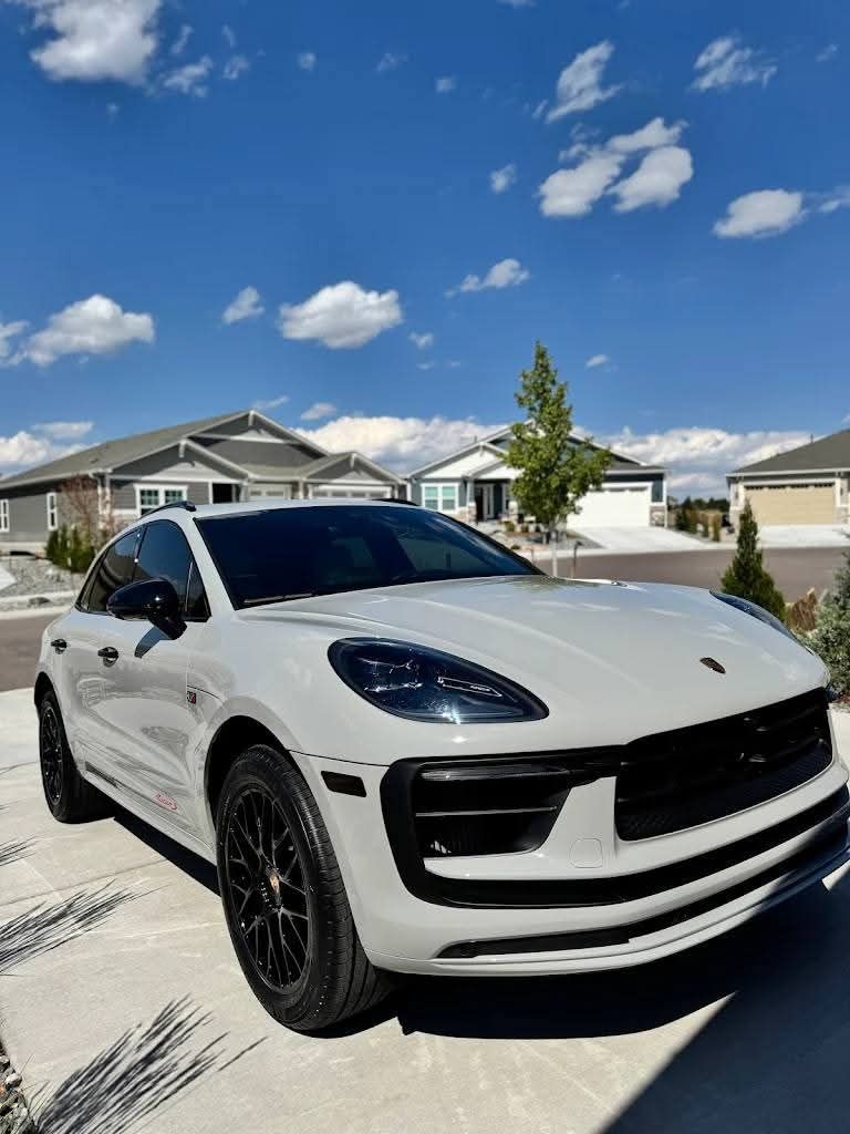 White sports SUV parked on a suburban street under a blue sky with clouds
