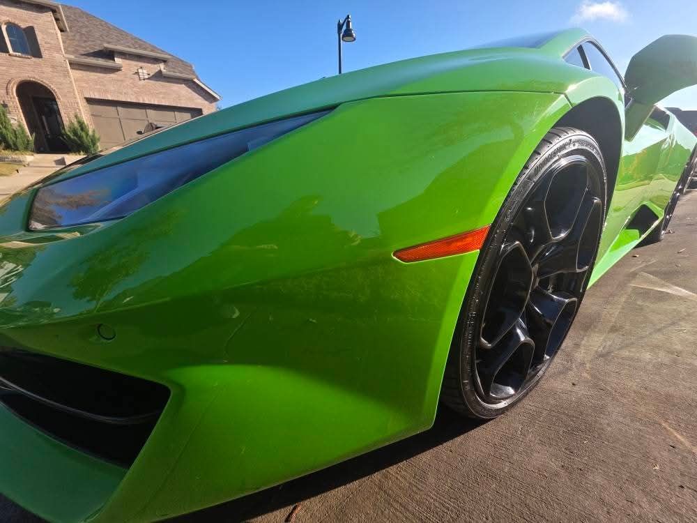 Bright green sports car parked outdoors, low-angle view of the front side and wheel