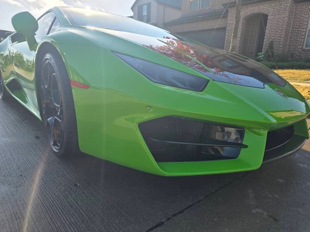 Green sports car parked in a driveway outside a house, front angle view