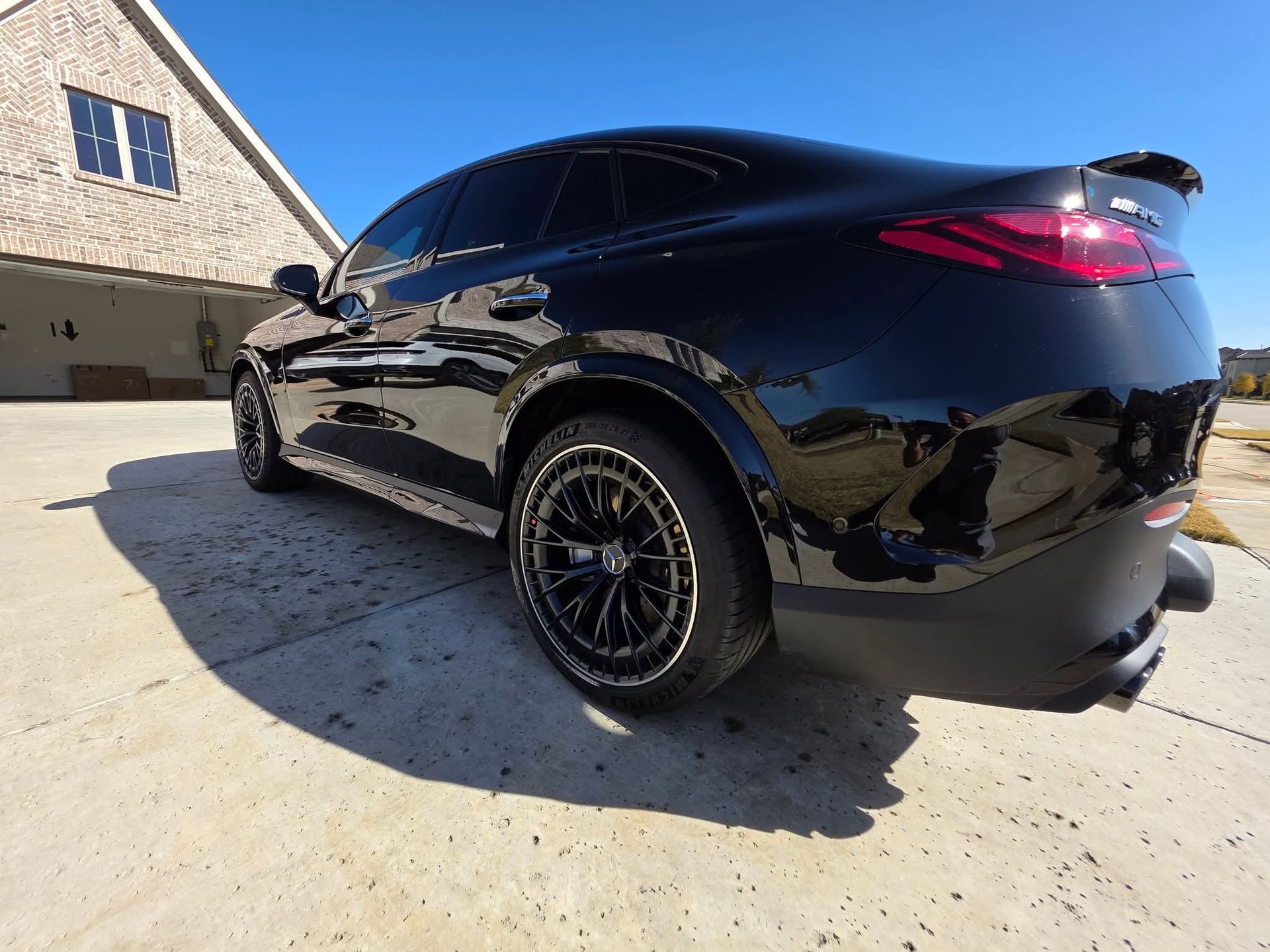 Black SUV parked in a driveway beside a stone house on a sunny day