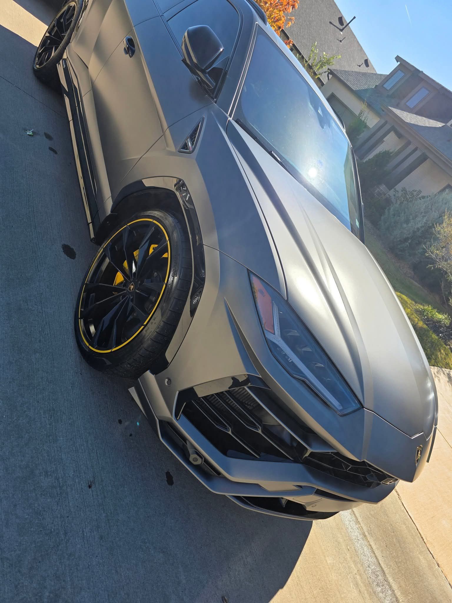 Gray sports sedan parked on a sunny street, angled front view with black rims and yellow brake calipers