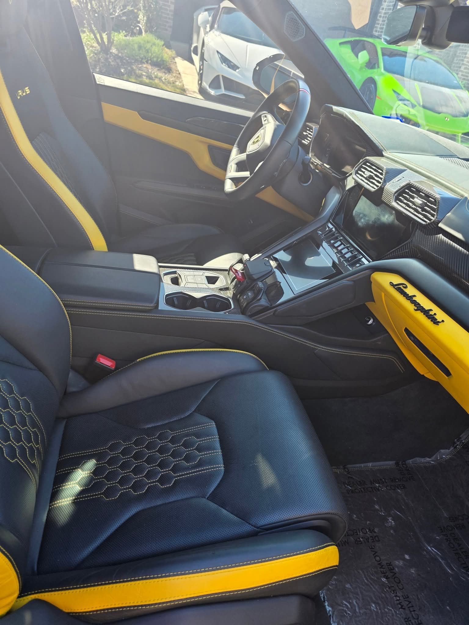 Black and yellow sports car interior with bucket seats, center console, and steering wheel in sunlight