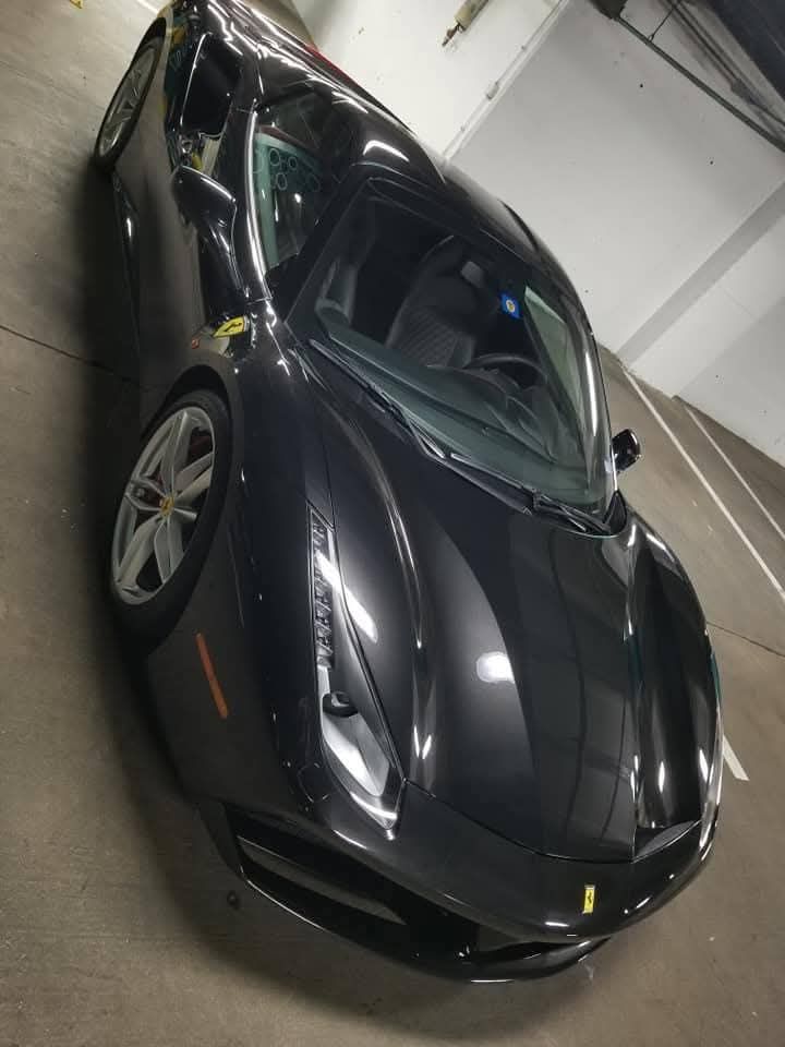 Black Ferrari sports car parked in an indoor garage, angled front view