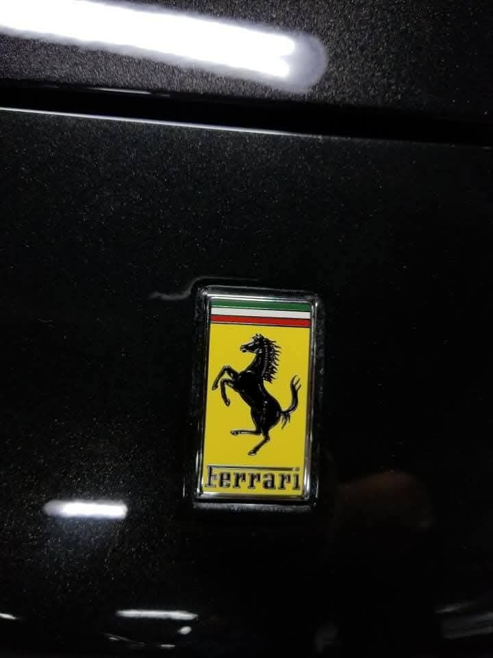 Close-up of a Ferrari emblem on a glossy black car hood