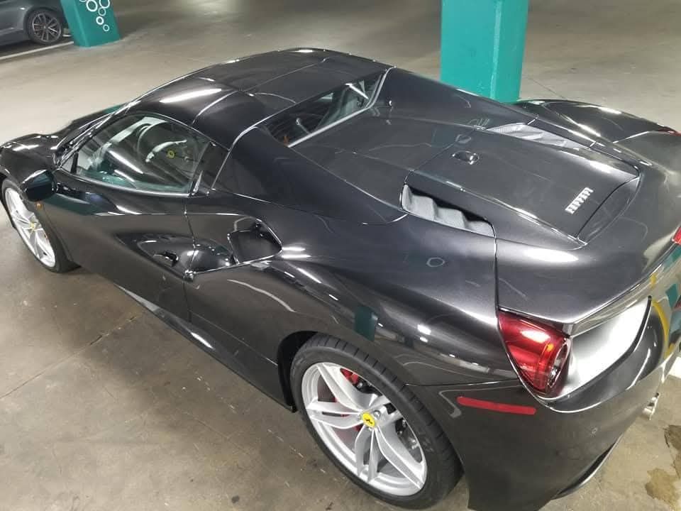 Black Ferrari sports car parked in a garage, viewed from the rear side